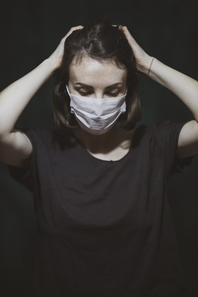 Frau Arzt mit Mundschutz schlägt Hände übern Kopf Stress