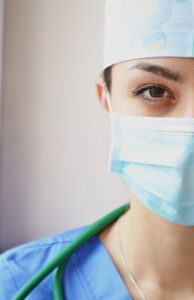 Ärztin mit Maske und OP-Outfit linke Gesichtshälfte zu sehen